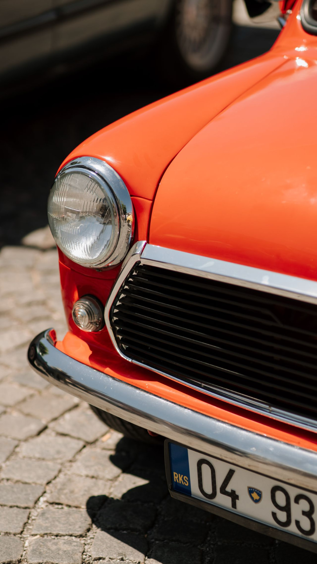 Vooraanzicht van een oranje klassieke Mini met chromen bumper en koplamp